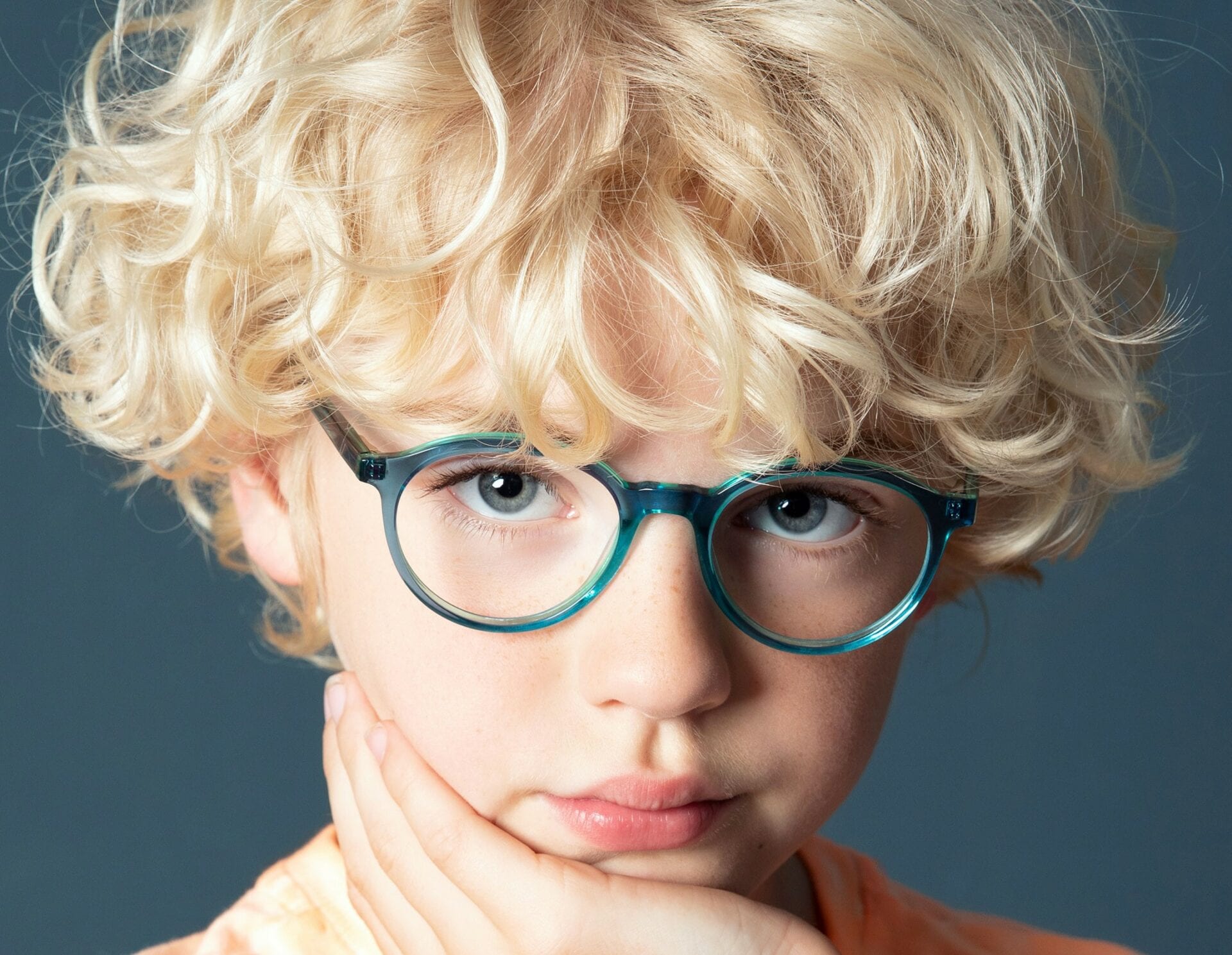 A young boy with blonde hair wearing glasses.