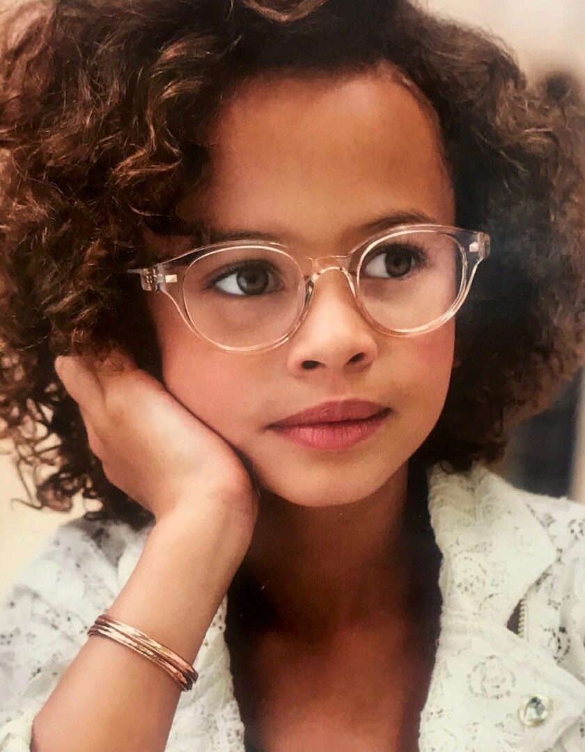 A young girl with glasses and curly hair.