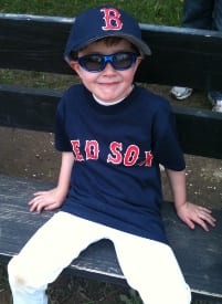 A young boy sitting on the bench at a baseball game.