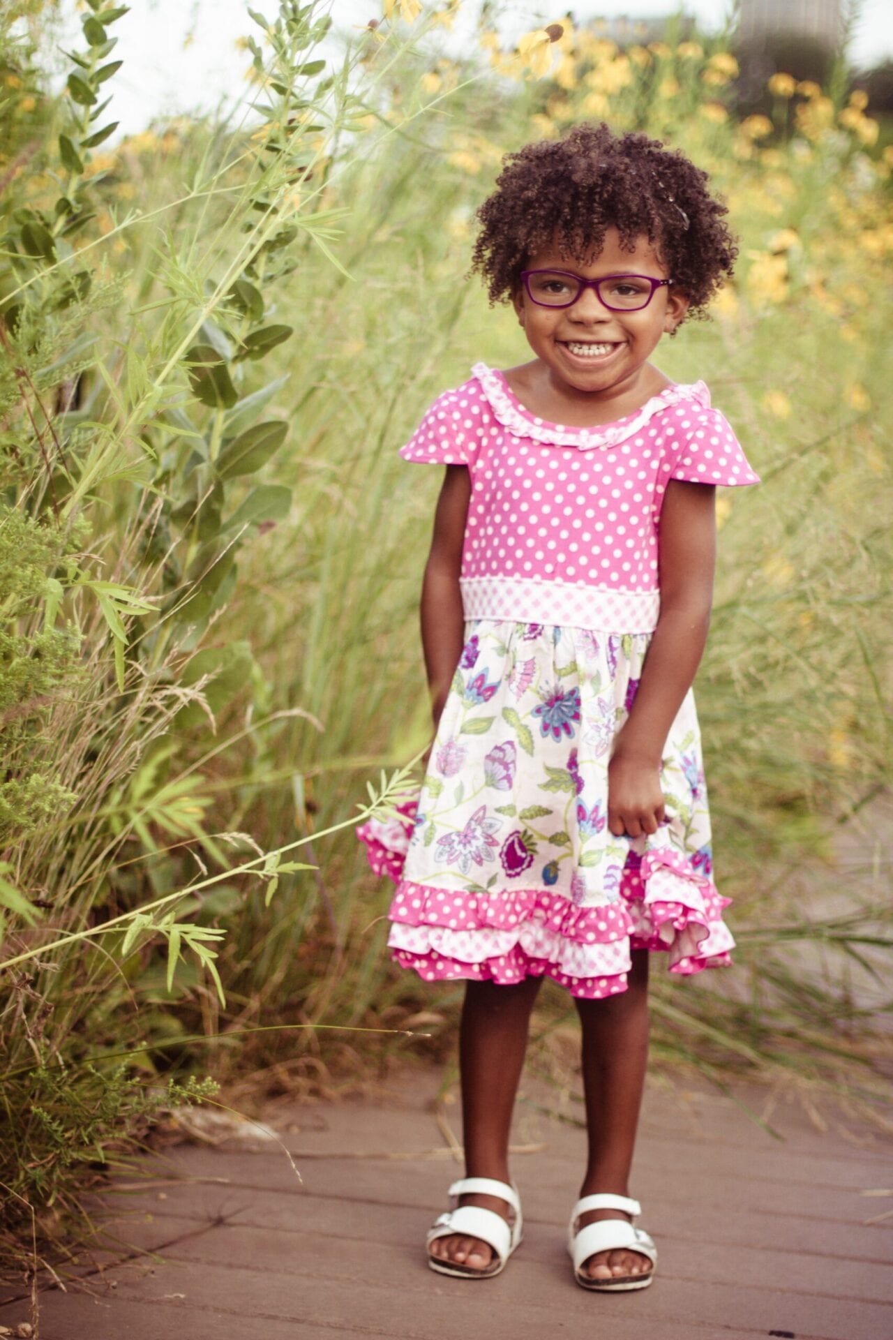 A little girl wearing glasses and a pink dress.