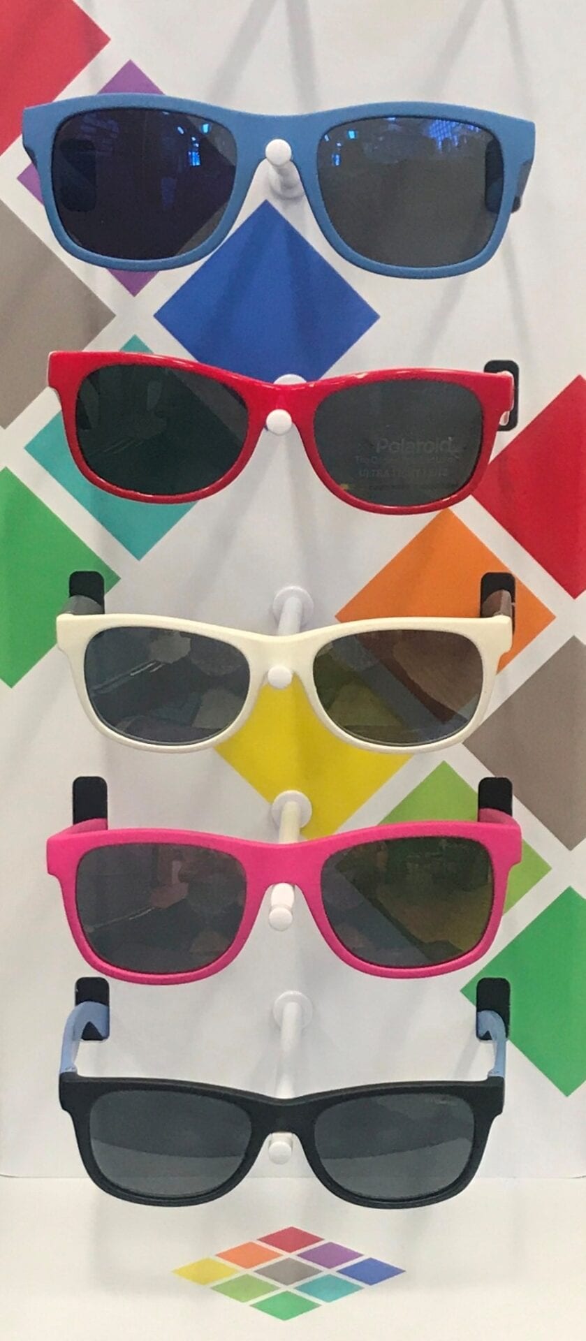 Three pairs of sunglasses are hanging on a wall.