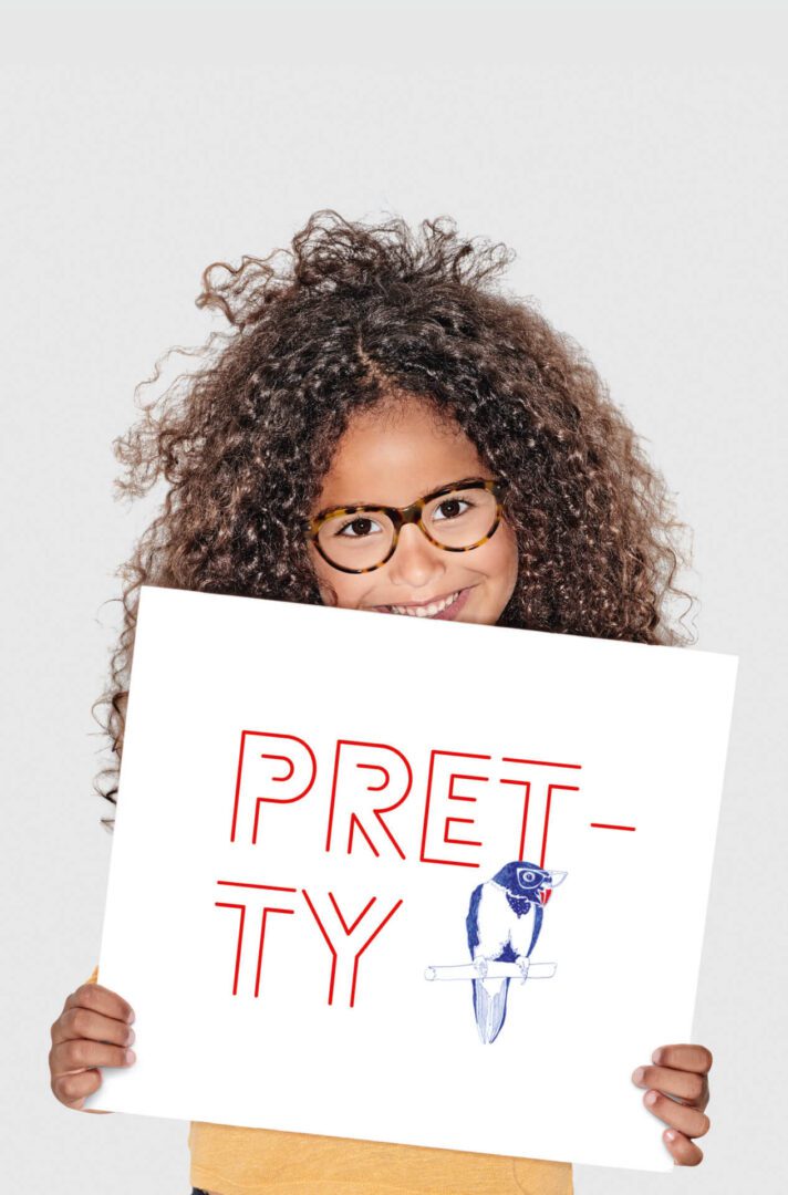 A girl holding up a sign that says pretty.